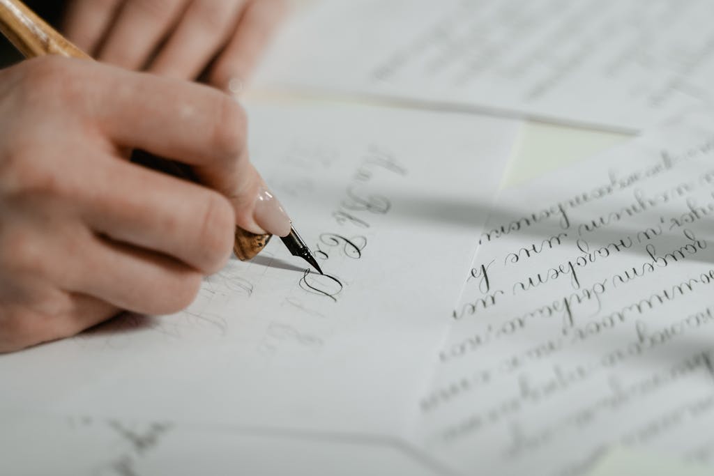 Close-up of a hand creating beautiful calligraphy on paper, showcasing intricate handwriting skills.